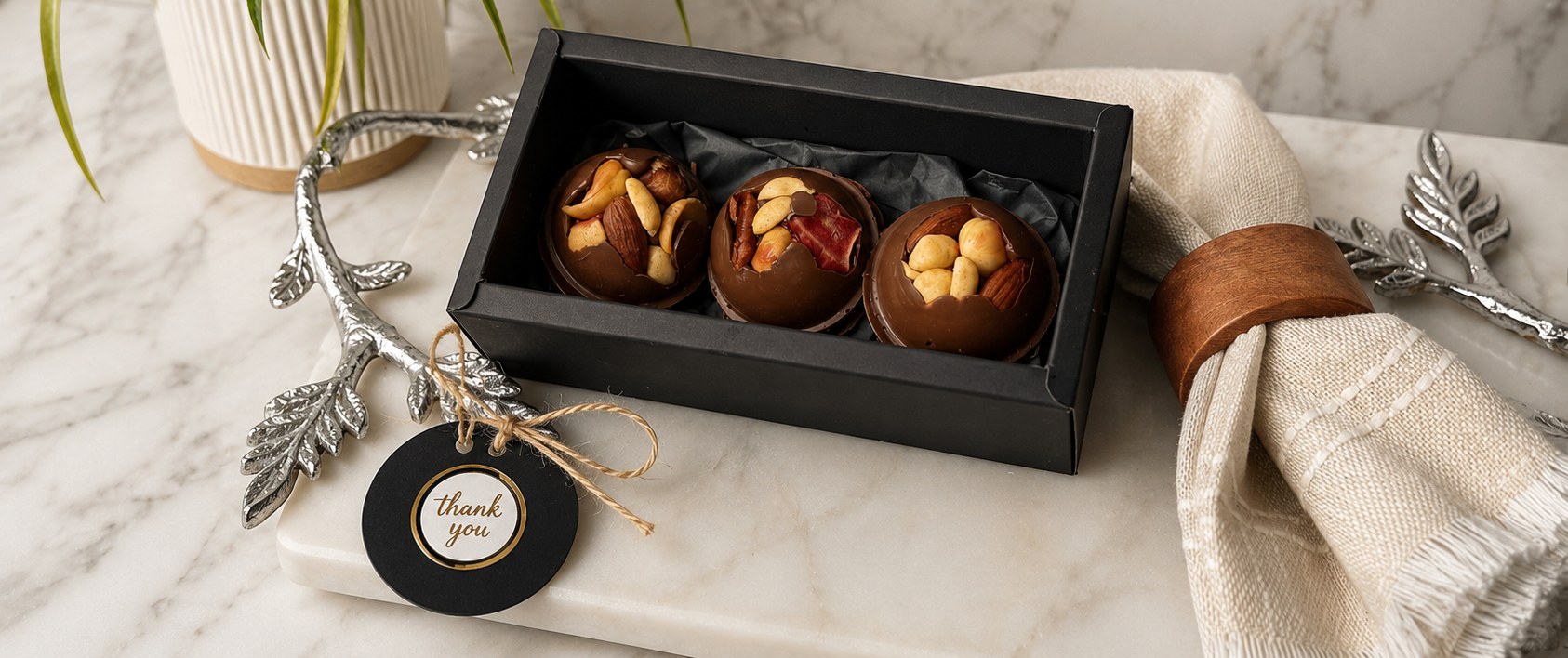 Three gourmet chocolate bombs in a black gift box with a thank you tag